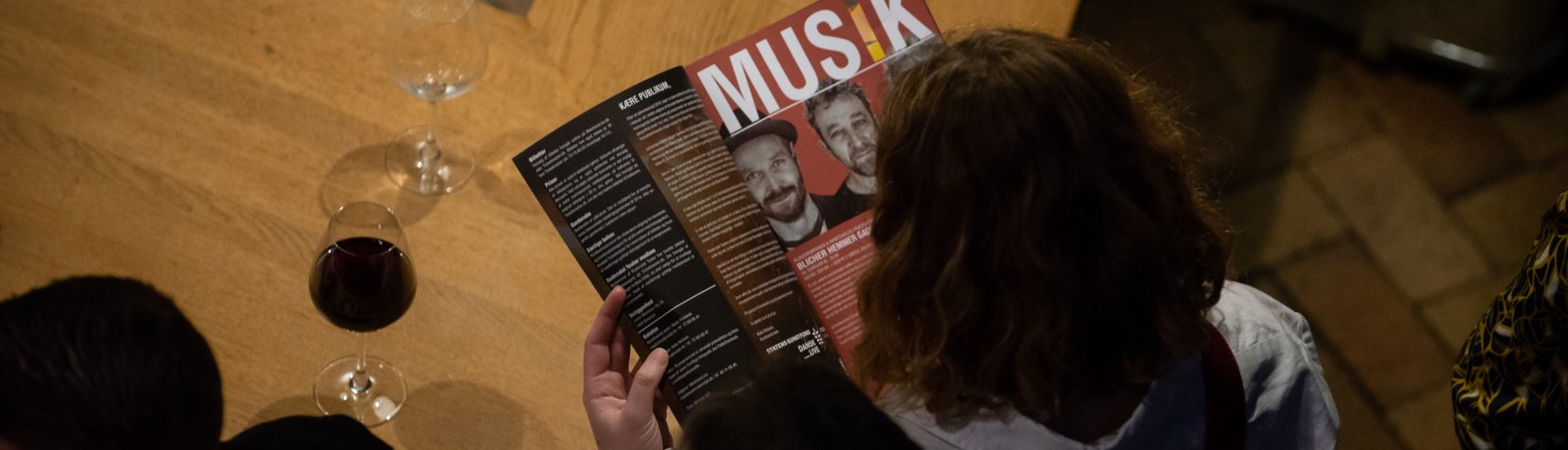 En gæst læser en side med overskriften MUSIK fra MantziusLives trykte program